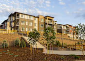 Thumbnail 25 of 28 - A large apartment complex with a staircase leading to the entrance.