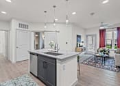 Thumbnail 16 of 20 - A modern kitchen with a large island and a dining area with a couch.