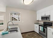 Thumbnail 6 of 30 - A kitchen with a black stove top oven and white cabinets.