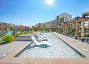 Thumbnail 33 of 38 - a resort style pool with lounge chairs in a large apartment building