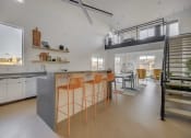Thumbnail 13 of 25 - clubroom kitchen with a large island with stools and  a staircase