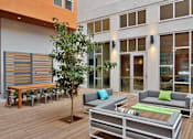 Thumbnail 4 of 13 - A patio with a tree, couch, and chairs.