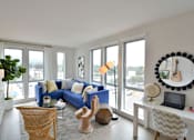 Thumbnail 7 of 13 - A living room with a blue couch and a guitar on the wall.