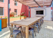 Thumbnail 5 of 13 - A long wooden table is surrounded by chairs on a patio.