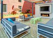 Thumbnail 9 of 13 - A patio with grey couches and a fireplace.