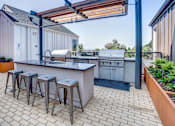 Thumbnail 1 of 13 - A patio with a bar and stools is surrounded by buildings.
