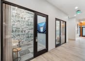 Thumbnail 25 of 30 - a corridor with glass doors and a lobby with chairs and a table