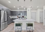 Thumbnail 10 of 20 - A modern kitchen with a marble island and two green chairs.