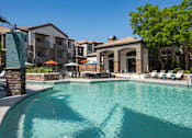 Thumbnail 19 of 48 - A swimming pool surrounded by lounge chairs and umbrellas in front of apartment buildings.