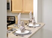 Thumbnail 26 of 37 - a kitchen with a sink and a counter top with plates and napkins on it