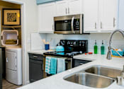 Thumbnail 8 of 44 - A kitchen with a stove, sink, and refrigerator.