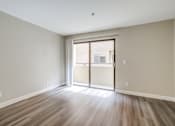 Thumbnail 9 of 51 - A room with a sliding glass door and wooden flooring.