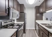Thumbnail 1 of 51 - A modern kitchen with dark brown cabinets and stainless steel appliances.