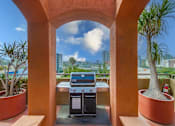 Thumbnail 22 of 51 - A BBQ grill is in the middle of a patio with a view of the city.