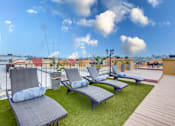 Thumbnail 23 of 51 - A patio with a wooden deck and grey cushioned lounge chairs.