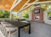 Thumbnail 28 of 38 - a covered patio with a large wooden table and chairs and a brick fireplace at Arbor Heights, Tigard, Oregon