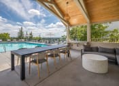 Thumbnail 29 of 38 - a patio with a table and chairs and a pool in the background at Arbor Heights, Tigard