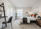 Thumbnail 8 of 48 - Bright bedroom with wooden nightstand and layered bedding at Canyon Creek Apartments, Wilsonville, Oregon