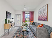 Thumbnail 14 of 20 - A living room with a grey couch and a large abstract painting on the wall.