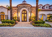 Thumbnail 55 of 57 - A house with a stone archway entrance and a brick pathway leading to it.