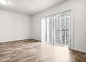 Thumbnail 8 of 29 - A room with a sliding glass door and wooden flooring.
