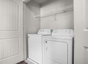 Thumbnail 5 of 29 - A white washing machine and dryer in a small laundry room.