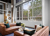 Thumbnail 11 of 30 - A living room with brown leather couches and a large window.