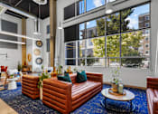 Thumbnail 9 of 30 - A living room with a blue carpet and brown leather furniture.