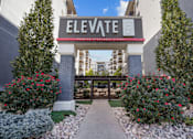 Thumbnail 27 of 30 - The entrance to the Elevate on 5th building is framed by bushes and trees.
