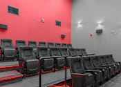 Thumbnail 14 of 30 - A row of black cinema seats with red lighting underneath them.