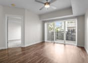 Thumbnail 7 of 30 - A room with a ceiling fan and sliding glass doors.