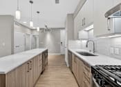 Thumbnail 16 of 33 - A modern kitchen with wooden cabinets and a white countertop.