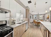 Thumbnail 9 of 33 - A modern kitchen with a black stove top oven and wooden cabinets.