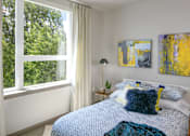 Thumbnail 7 of 30 - A bedroom with a bed, a nightstand, and a window with curtains