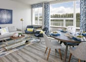 Thumbnail 3 of 30 - A modern living room with a grey sofa, a coffee table, and a dining table.