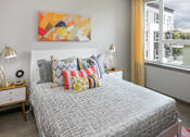 Thumbnail 11 of 30 - A bedroom with a bed, nightstand, and a painting on the wall