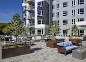 Thumbnail 23 of 30 - A modern building with a patio area in front.