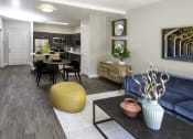 Thumbnail 4 of 25 - a living room with a couch and a table in front of a kitchen
