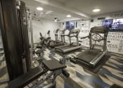 Thumbnail 21 of 25 - a gym with treadmills and other exercise equipment in a room with TV's on the wall