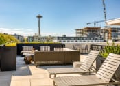 Thumbnail 11 of 30 - a rooftop patio with chairs and tables and a city in the background