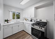 Thumbnail 12 of 55 - One-Bedroom Affordable Apartments in San Mateo, CA - Hillsdale Garden - Kitchen with Modern Appliances, White Cabinetry, and Hardwood-Style Flooring