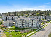 Thumbnail 1 of 50 - A row of modern apartment buildings are surrounded by trees and grassy areas.