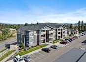 Thumbnail 44 of 50 - A large apartment complex with multiple buildings and cars parked in the lot.