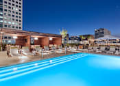 Thumbnail 13 of 24 - A swimming pool with chairs around it at night.