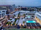 Thumbnail 20 of 24 - A rooftop pool area with a view of the city at dusk.