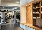 Thumbnail 20 of 41 - A gym with a variety of equipment and a wooden shelf with towels.