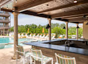 Thumbnail 31 of 41 - A poolside bar area with striped chairs and a black counter.