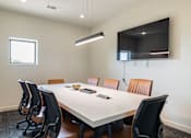 Thumbnail 26 of 41 - A conference room with a white table and brown chairs.