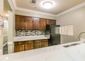 Thumbnail 20 of 21 - A kitchen with a black refrigerator and wooden cabinets.