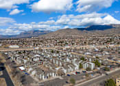 Thumbnail 8 of 21 - A residential area with houses and cars under a blue sky with clouds.
